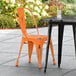 A Lancaster Table & Seating distressed orange chair on a black outdoor patio table.