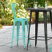 Two Lancaster Table & Seating Distressed Seafoam metal bar stools on a patio.