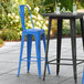 Two Lancaster Table & Seating distressed blue metal barstools on an outdoor patio table.