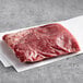 A piece of raw Warrington Farm Meats flank steak on a white surface