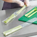 A woman in gloves cutting celery on a cutting board and placing it in a Choice clear polyethylene layflat bag.