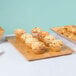 An American Metalcraft rectangular bamboo platter holding a group of muffins on a table in a bakery.