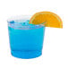 A blue drink with an orange slice in a clear plastic tumbler.