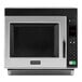 An Amana stainless steel commercial microwave with a black door.