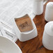 A white Tablecraft melamine dish with sugar packets in it.