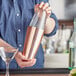 A woman using an Acopa copper cocktail shaker.