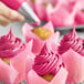 A close-up of a cupcake with pink frosting made using Chefmaster Fuchsia Liqua-Gel Food Coloring.