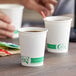 Two EcoChoice white paper cups with coffee on a table.