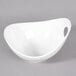 A white porcelain bowl with cut outs on a gray surface.