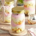 A group of Acopa Rustic Charm mason jars filled with dessert with spoons on a pink napkin.