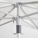 A close up of a white Lancaster Table & Seating umbrella with metal poles.