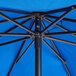 A Pacific blue Lancaster Table & Seating umbrella with black poles.