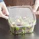 A person in gloves holding a clear plastic Choice deli container with a salad inside.