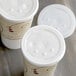 Two Solo translucent plastic lids with straw slots and identification buttons on white cups.