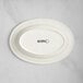 An ivory oval stoneware platter with green bands and black text reading "Acopa" on it.