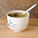 A Blue Bamboo melamine miso bowl with a lid filled with soup and a spoon.