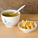 A blue Thunder Group Blue Bamboo melamine miso bowl with a lid filled with soup next to a cup of soup and a spoon.