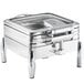 An Acopa stainless steel chafer with a glass lid on a counter.