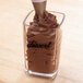 A Cambro square plastic shot glass filled with chocolate frosting.
