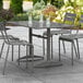 A Lancaster Table & Seating gray outdoor dining table with a drink on it.