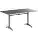 A gray Lancaster Table & Seating outdoor dining table with a metal base and umbrella hole.