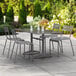A Lancaster Table & Seating gray aluminum dining table with chairs on an outdoor patio.