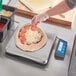 An AvaWeigh pizza scale on a counter with a pizza being weighed.