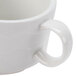 A close-up of a CAC Goldbook white bone china tea cup with a handle.