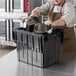 A man in an apron putting pots into a large black Choice chafer tote.