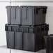 A stack of black plastic Choice Chafer Tote storage boxes.