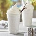 Two cups of Capora Vanilla Bean Frappe with whipped cream and a straw.