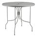 A Lancaster Table & Seating round outdoor table with ornate metal legs and a metal base.