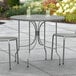 A Lancaster Table & Seating Harbor Gray outdoor patio table with ornate legs.