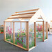 A Whitney Brothers wood play greenhouse with a flower garden on the side.