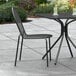 A Lancaster Table & Seating Harbor Black outdoor chair and table on a patio.