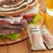 A sandwich with meat and vegetables on a wooden plate with Heinz Horseradish Sauce.