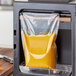 A VacPak-It chamber vacuum packaging machine sealing a bag of orange juice.