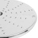 A circular metal Robot Coupe grating/shredding disc with holes in it.