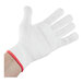 A hand wearing a white Mercer Culinary Millennia Level Cut-Resistant glove with red trim.