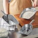 A woman using a Choice aluminum scoop to fill a metal pan with flour.
