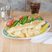 A Diamond Barcelona oval platter with a sandwich, chips, and vegetables on a table.