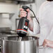 A chef using a Sammic medium-duty hand blender to mix something in a metal pot.