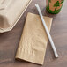 A brown EcoChoice WrapNap paper napkin and straw on a table.
