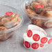 A roll of red Point Plus Spicy food labeling stickers next to plastic containers of chicken.