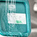 A water pouring onto a plastic container with a green Noble Products food label.