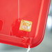 A red plastic container with a yellow Noble Products Tuesday day of the week sticker on it.