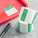 A red tray with a roll of green and white paper labels next to a Noble Products Friday label.
