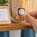 A hand placing a dissolvable clock label on a glass jar containing biscotti.