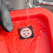 A dissolvable clock label being rinsed with water in a red container.