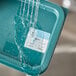 A Noble Products Monday dissolvable food labeling sticker being placed on a plastic container full of water.